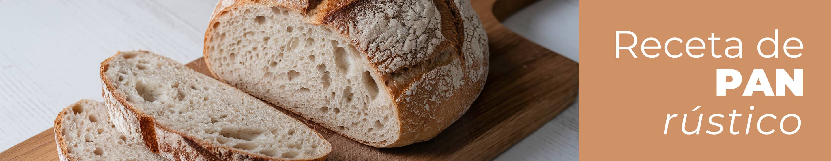 Hogaza de pan rústico casero horneado con ingredientes Dia, colocada sobre una mesa de madera de cocina con un paño de tela, cortada en cuatro rebanadas grandes donde se aprecia la miga esponjosa y la corteza crujiente.